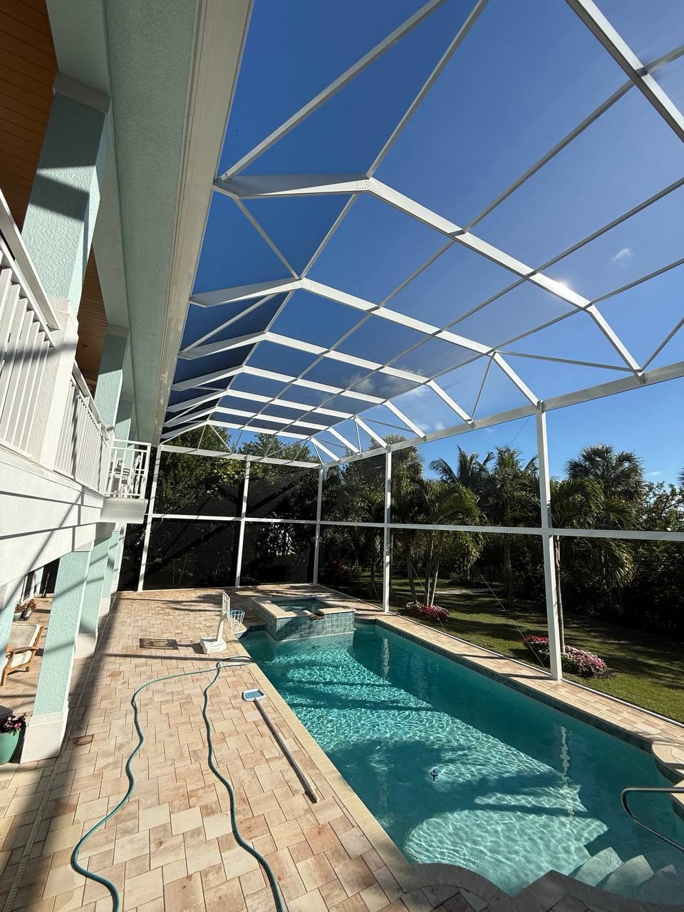 White aluminum pool cage roof framing under a clear Florida sky