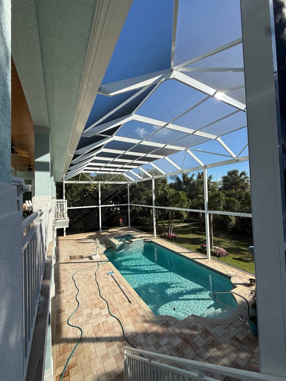 Full length pool cage roof extending along the two story residence
